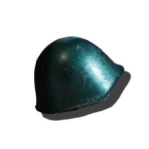 May include: A metallic dark green helmet with a smooth, rounded dome shape and a slightly flared brim. The surface features a reflective, glossy finish that catches the light, highlighting the curved contours of the protective headgear.