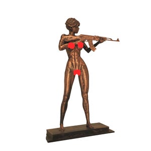 May include: A bronze-colored sculpture of a nude figure holding a rifle, standing on a rectangular base. The figure has red coverings over the nipples and pubic area. The sculpture is set against a white background.