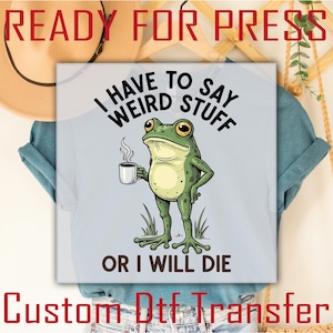 May include: Light blue t-shirt featuring a cartoon frog holding a coffee cup. The frog has green skin and is standing upright. Text on the shirt reads "I HAVE TO SAY WEIRD STUFF OR I WILL DIE". The words "READY FOR PRESS" and "Custom Dtf Transfer" are also visible.