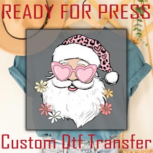 Puede incluir: Un diseño gráfico con Papá Noel con gafas de sol rosas en forma de corazón y un sombrero con estampado de leopardo. La imagen incluye el texto "READY FOR PRESS" en la parte superior y "Custom Dtf Transfer" en la parte inferior. Flores alrededor de la cara de Papá Noel.