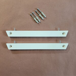 May include: Two white wooden shelf brackets with pre-drilled holes and four silver screws.