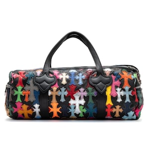 May include: Black leather duffel bag featuring a colorful cross pattern. The bag has two black handles and a zipper closure. The crosses are in various colors, including red, blue, yellow, and green.