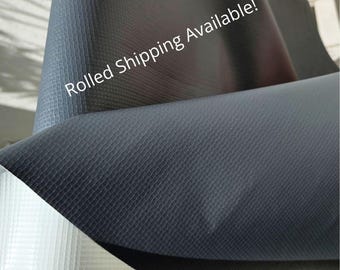 May include: Close-up of a rolled, dark gray textured material. The material has a subtle grid pattern and is folded over itself. The text "Rolled Shipping Available!" is printed on the material.