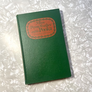 May include: A green hardcover book with a brown title label that reads "Miss Pennyfeather and the Pooka" by Eileen O'Faolain.