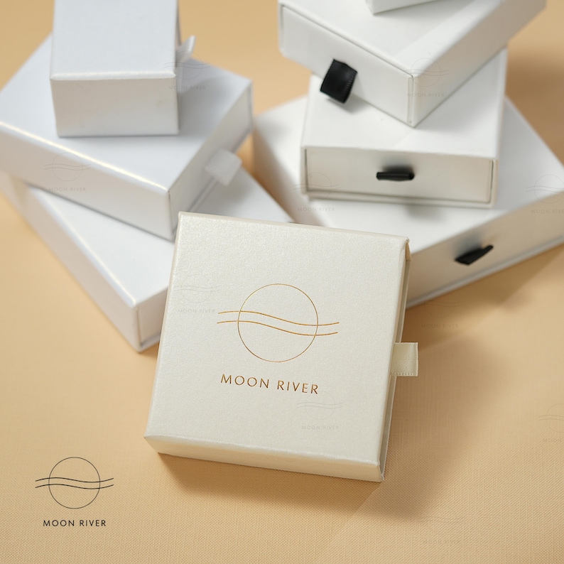 May include: White gift boxes with a gold logo of a circle with a wavy line inside and the text "MOON RIVER".
