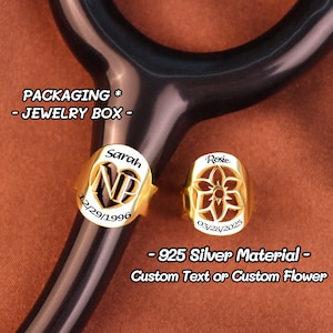 May include: Two gold-coloured stethoscope charms. One charm has the name "Sarah", initials "NP", and the date "12/29/1996". The other charm has the name "Rosie" and the date "03/28/2025". The charms are made of 925 silver and can be customised with text or a flower design.