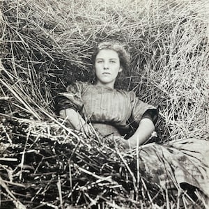Tarjeta de felicitación con foto vintage Mujer joven soñando en una pila de heno