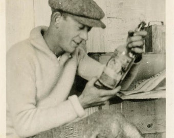 Vintage Snapshot 1920 YOung Man Wool Cap Looks at Bottle of Whiskey 55K
