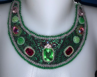 Collana bavaglino “treccia verde”. Pezzo unico. Decorato con bellissimi strass Swarovski nei toni del rosa e del verde. Ricamo di perline.