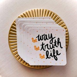 May include: A stack of white square stickers with gold glitter. The stickers have black lettering that reads "the way, the truth, the life".