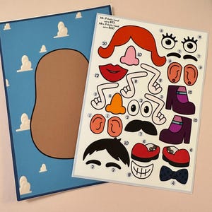 May include: A Mr. Potato Head craft kit with various facial features and accessories. The kit includes a blue background with a brown potato head shape and a sheet of cut-out pieces. Text on the sheet reads "Mr. Potato head save £62" and "Mrs. Potato head save £130."