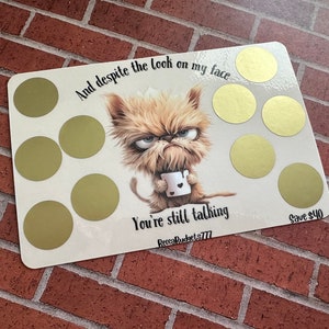 May include: A white card with a cartoon illustration of a furry creature holding a cup. The card has gold circles with text that reads "And despite the look on my face You're still talking Save $40".