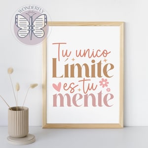 May include: A framed print with the text "Tu unico Limite es tu mente" in brown and pink lettering. The print is in a light wood frame and features a heart and flower graphic. A vase with dried flowers is in the foreground.