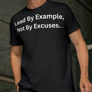 Puede incluir: Camiseta negra con texto blanco que dice "Lead By Example, Not By Excuses..."