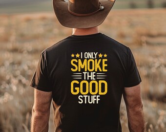 May include: A person wearing a black t-shirt with the text "I only smoke the good stuff" in yellow. The person is wearing a brown cowboy hat and is standing in a field.