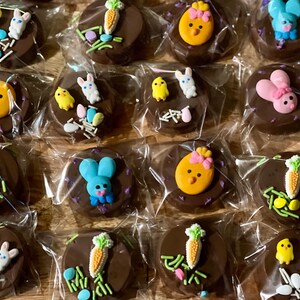 Puede incluir: Galletas cubiertas de chocolate decoradas con caramelos tem&aacute;ticos de Pascua. Cada galleta est&aacute; envuelta individualmente y presenta dise&ntilde;os coloridos de conejitos, pollitos y zanahorias, junto con chispas y huevos de colores pastel. Un dulce festivo para las fiestas.