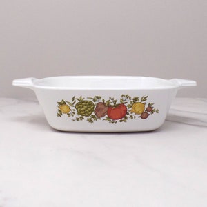 May include: White rectangular baking dish with a green, yellow, red, and brown floral pattern of vegetables and herbs.