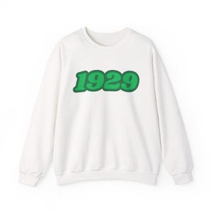 Może przedstawiać: Biała bluza z zielonym nadrukiem 1929 z przodu.