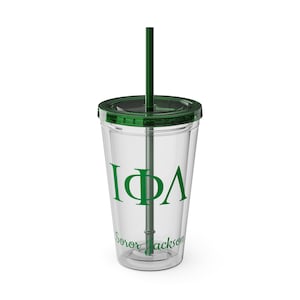 May include: A clear plastic tumbler with a green lid and straw. The tumbler has the letters "IΦΛ" and the text "Soror Jackson" printed on it.