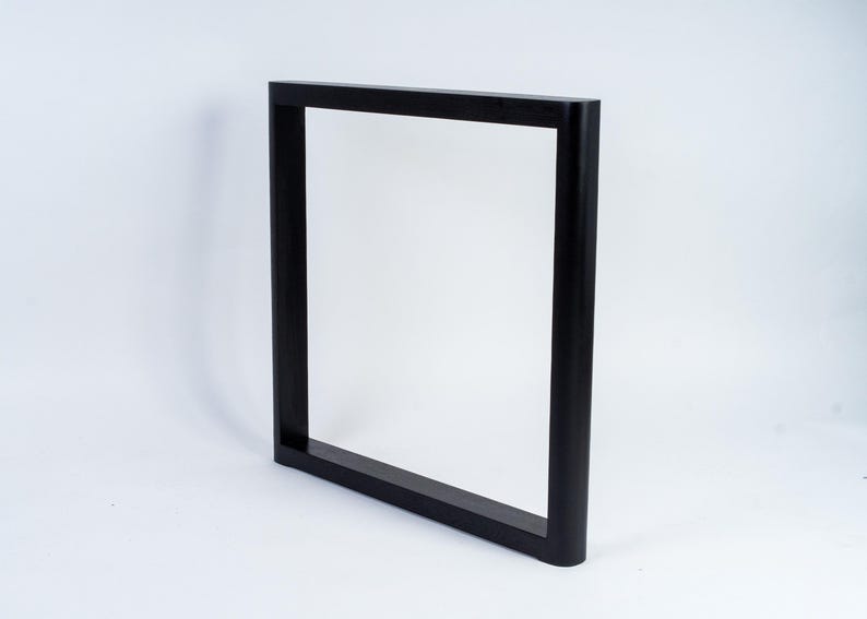 May include: A black, rectangular frame with a square profile. The frame is made of a solid material and has a matte finish. The frame is designed to stand upright and is suitable for various uses.