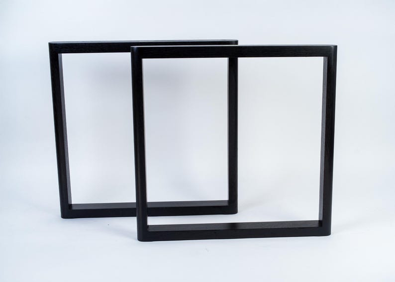 May include: Two black, rectangular table legs. The legs are made of solid wood and have a modern, minimalist design. The legs are shown against a white background.