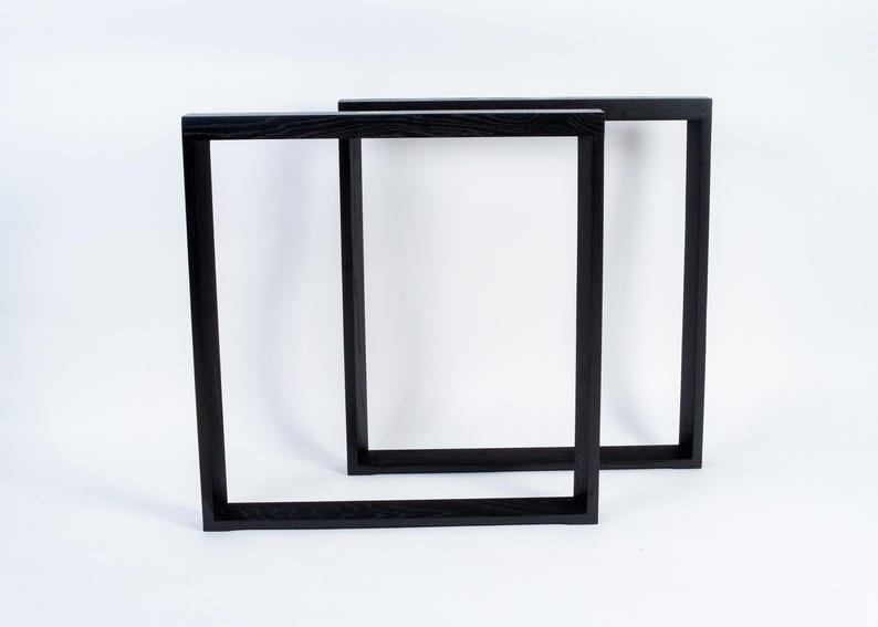 May include: Two black wooden picture frames, rectangular in shape, are displayed against a white background. The frames are empty, with a simple, modern design. The frames are likely for displaying art or photographs.