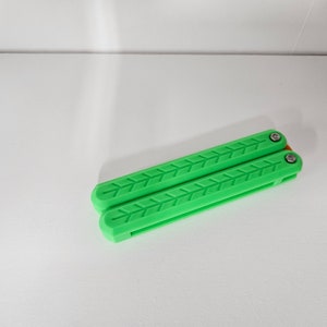 May include: A green plastic butterfly knife with a textured pattern on the handle.