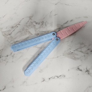 May include: A blue and pink plastic butterfly knife. The knife is closed and has a textured design.