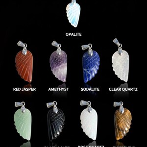 May include: A collection of gemstone wing pendants in various colors, including red jasper, amethyst, sodalite, and clear quartz. Each pendant has a silver-colored bail. The image also includes pendants made of green aventurine, black agate, rose quartz, and tiger's eye.