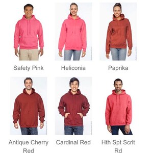 May include: A collection of six hooded sweatshirts in various colors, including Safety Pink, Heliconia, Paprika, Antique Cherry Red, Cardinal Red, and Hth Spt Scrlt Rd. Each sweatshirt features a drawstring hood and a front pocket. The names of the colors are displayed below each sweatshirt.