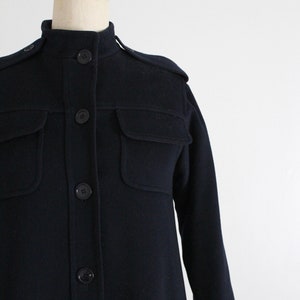 May include: A navy blue long-sleeved shirt with a collared neckline and button closure. The shirt has two flap pockets on the chest and a slightly A-line silhouette.