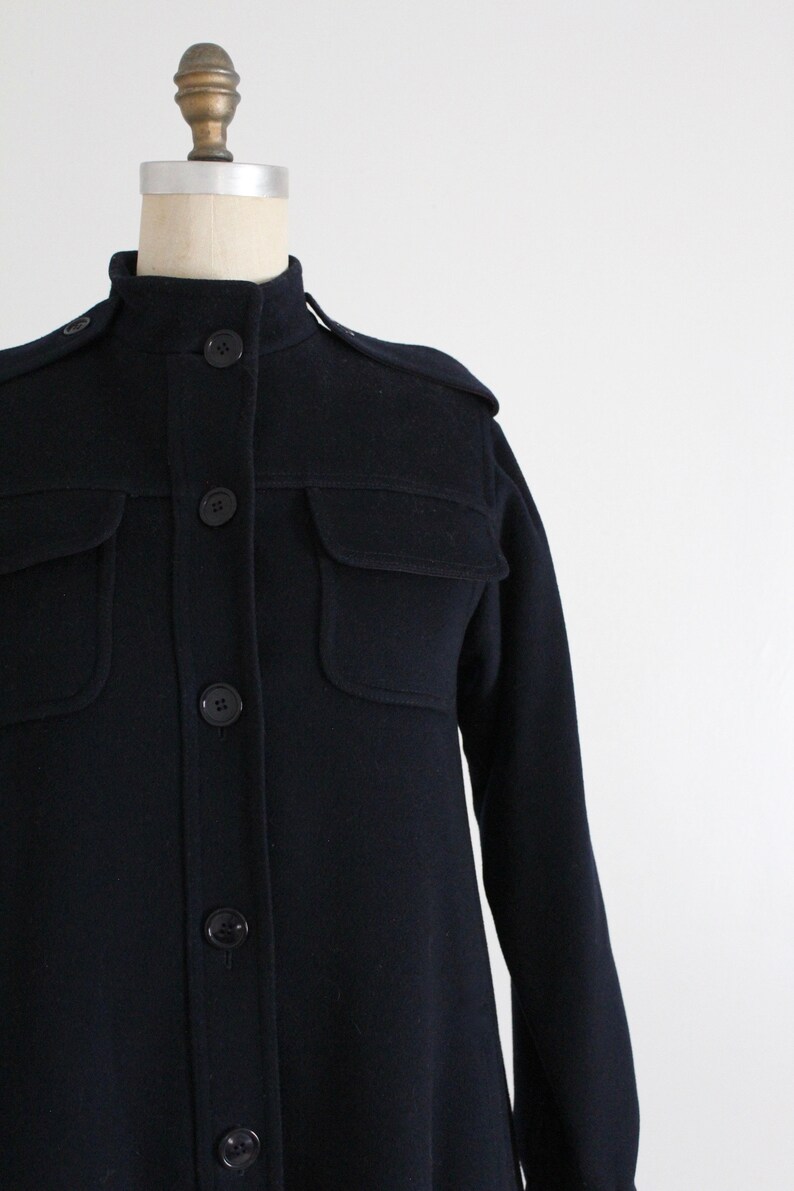 May include: A navy blue long-sleeved shirt with a collared neckline and button closure. The shirt has two flap pockets on the chest and a slightly A-line silhouette.