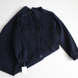May include: A navy blue long-sleeved jacket with a stand-up collar, four pockets, and button closures.