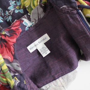 May include: A purple hooded jacket with a floral print and a zipper closure. The jacket has a label that reads "Banana Republic" and a size tag that reads "XS".
