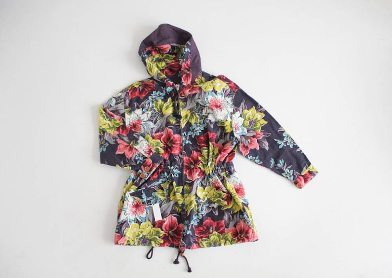 May include: A hooded jacket with a floral print featuring pink, yellow, and blue flowers on a dark purple background.