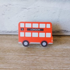 Puede incluir: Un juguete de autobús de dos pisos rojo con el número 5 y la palabra "LONDON" impresa en el lateral.