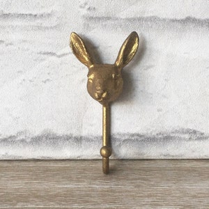 May include: A gold-colored rabbit head hook. The hook is made of metal and has a simple design. It would be a great addition to a farmhouse or rustic decor.