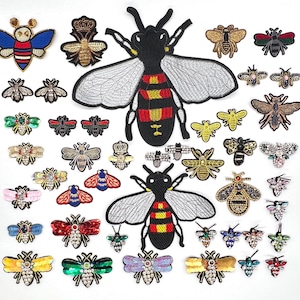 May include: A selection of embroidered bee patches in diverse sizes and styles. The patches showcase a range of colours, including gold, black, red, blue, and green, with detailed embroidery and adornments. Some patches are adorned with crowns.