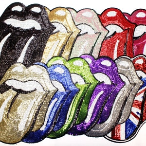 Puede incluir: Una colección de parches de labios con lentejuelas en varios colores, incluyendo negro, dorado, rosa, rojo, azul, verde, morado, plateado y un diseño de la bandera británica. Los parches están dispuestos en un patrón en capas, mostrando el icónico logo de la lengua y los labios.