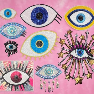 May include: A selection of sequined eye patches in various sizes and designs, featuring blue, white, yellow, and pink colours. Some patches have star and fringe accents, while others have a simple eye shape.