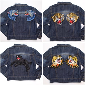 May include: Four denim jackets with embroidered animal patches. The jackets feature patches of wolves, tigers, and a panther. The jackets are a medium wash denim with button closures and pockets.