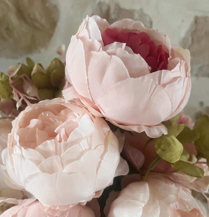 May include: A bouquet of pink and white peonies with green leaves. The peonies are in full bloom and have a delicate, ruffled texture.