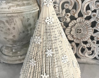 May include: A white book page Christmas tree with a rustic brown star on top and white snowflake embellishments.