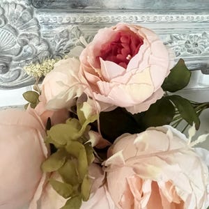 May include: A bouquet of pink peonies with green leaves. The flowers are arranged in a vase and are in focus. The background is out of focus.