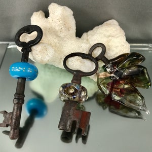 Peut inclure: Trois clés anciennes avec des perles de verre décoratives. Les clés sont en métal et ont un aspect rustique et vieilli. Les perles sont colorées et ont un aspect unique et fait main.