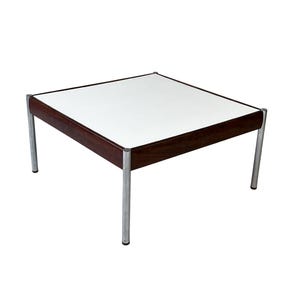 Puede incluir: Mesa de centro cuadrada con tapa blanca y borde de madera marrón oscuro. La mesa tiene cuatro patas de metal plateado. La mesa tiene forma cuadrada y es de diseño moderno de mediados de siglo.
