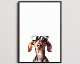 May include: A framed wall art print featuring a brown and black dachshund dog wearing black-rimmed sunglasses. The dog is centered against a plain white background, with its long ears hanging down and its nose visible below the glasses.