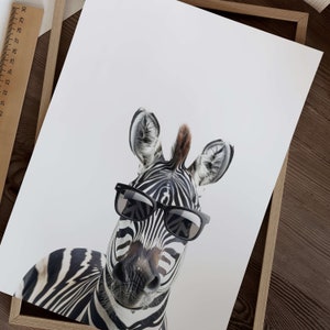 May include: A black and white zebra wearing black sunglasses. The zebra is looking directly at the camera. The background is white.