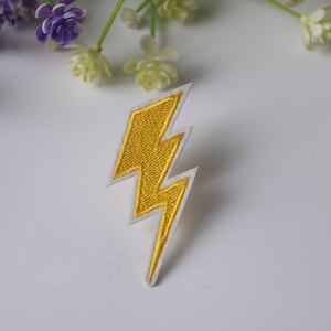 Peut inclure: Patch thermocollant en forme d'éclair jaune. Le patch est blanc avec une broderie jaune.