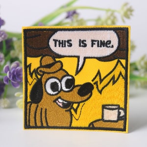 May include: Iron-on patch featuring an embroidered cartoon dog wearing a hat, sitting in a burning house, with the text "This is fine." in a speech bubble above the dog.